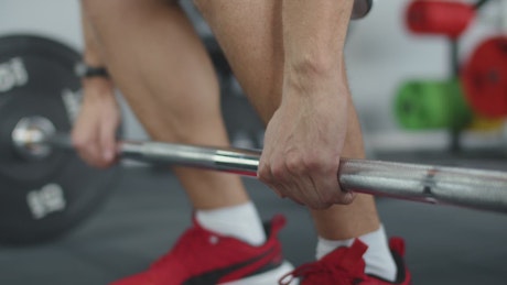 Close up of a person lifting a heavy barbell in the gym.