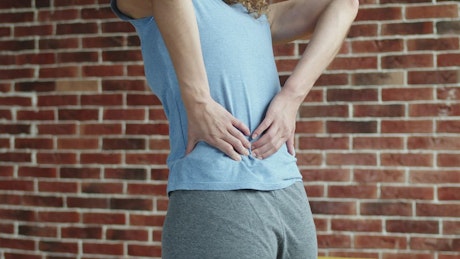 Close up of a person massaging their back in pain.