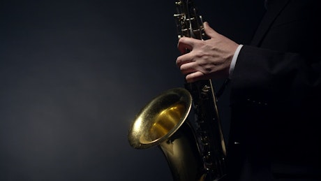 Close up of a Saxophonist playing the blues against a dark backdrop.