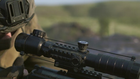 Close up of a sniper checking the scope of a rifle.