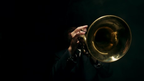 Close up of a trumpet being played on a black background.