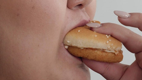 Close up of a woman eating a burger.