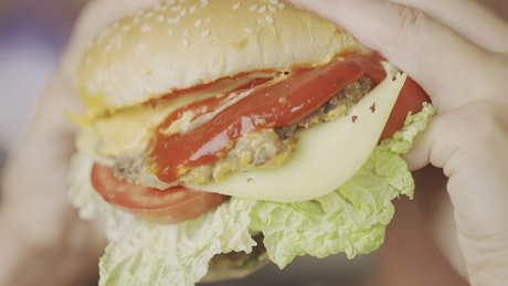 Close up of a woman eating a hamburger.