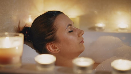 Close up of a woman relaxing in a bubble bath at home.
