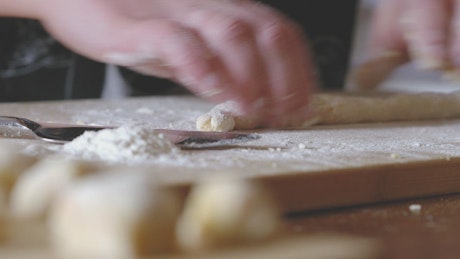 Close up of a woman rolling the dough for making gnocchi.