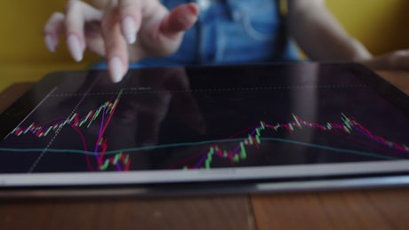 Close up of a woman tracking stock prices on a tablet.