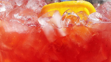 Close up of an ice jug of fruit punch being stirred.
