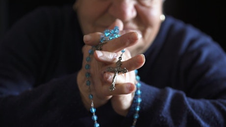Close up of prayer hands with rosary.