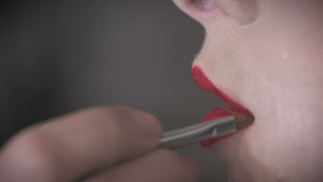 Close up of red lipstick being applied.