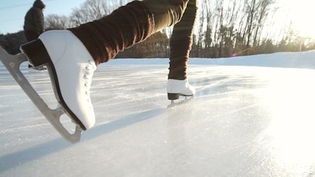 Close up of someone skating on an outdoor ice rink.