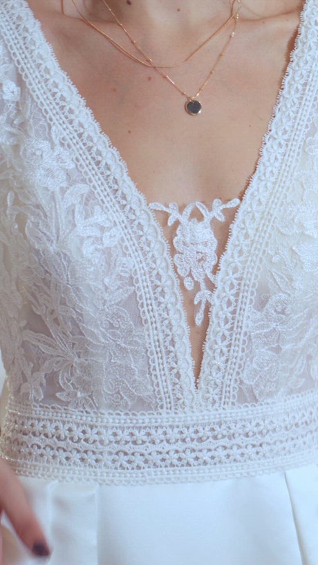 Close up shot at the intricate details of a wedding gown and a happy bride.
