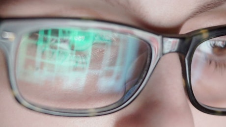 Closeup of surfing internet reflected in glasses.