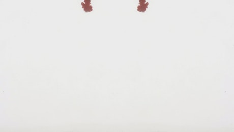 Cloud of red ink in water, mirroring, on white background.