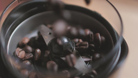 Coffee beans falling into a coffee pot.