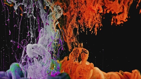 Colorful ink swirling through water against a dark background.