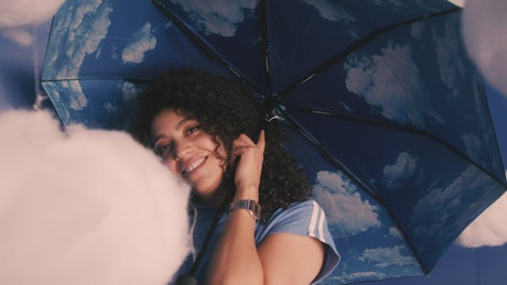Conceptual portrait of a girl with umbrella with clouds