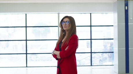 Confident businesswoman in a red blazer standing in a co-working space.