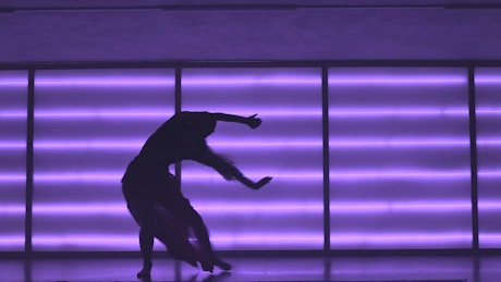 Contemporary dancer in neon-lit studio.