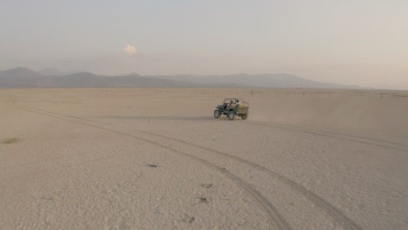 Convertible Jeep crossing a large desert in aerial shot