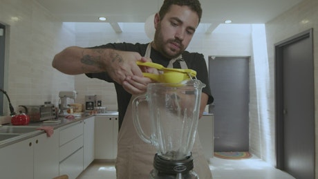Cook adding lemon to a blender.