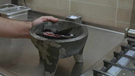 Cook grinding chilies in a molcajete.