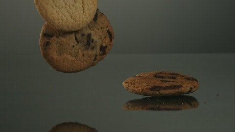 Cookies falling in slow motion to mirror surface.