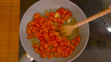 Cooking tomatoes and garlic in a frypan.