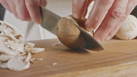 Cook's hands cutting mushrooms.