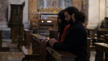 Couple at a church kneeling and praying.