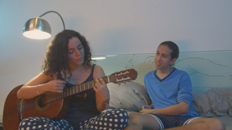 Couple hanging out while she plays guitar.