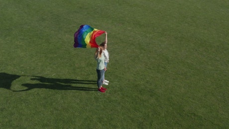 Couple holding a rainbow flag in the wind.