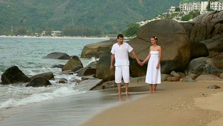 Couple holding hands walking in the beach.