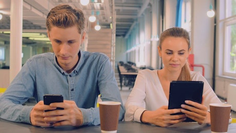 Couple in a cafe connected on their devices.