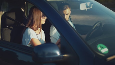 Couple in car check GPS with mobile phone