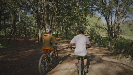 Couple of cyclists riding through nature together.