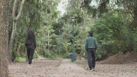 Couple of man and woman walking apart through a forest.