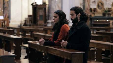 Couple praying at a church.