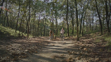 Couple riding bicycles in a forest.