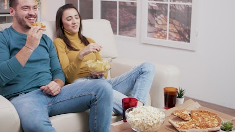 Couple sharing a pizza and popcorn.