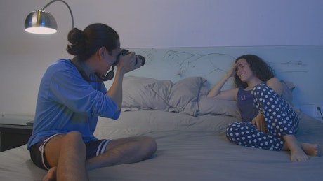 Couple taking pictures on bed.