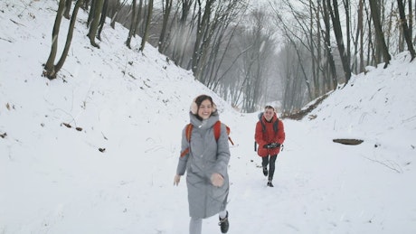 Couple walking happily through a forest while snowing