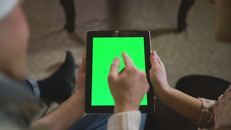 Couple watching together a tablet with green chroma.