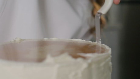 Covering a cake with icing in a close shot.