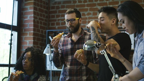Coworkers eating pizza in the office