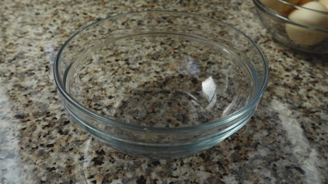 Cracking a raw egg into a glass bowl