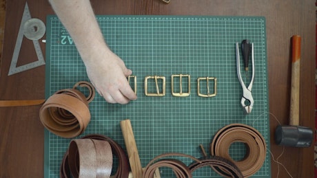Craftsman crafting a belt from tan leather.