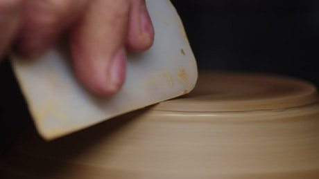 Craftsman using a smoothing tool to finish a handmade vase.