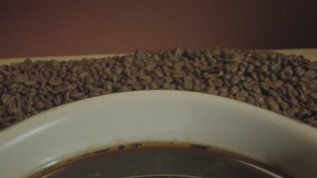 Cup of coffee among many coffee beans.