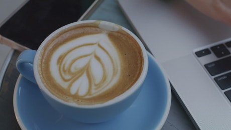 Cup with latte art next to a laptop