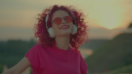 Curly redhead girl listening to music outdoors.